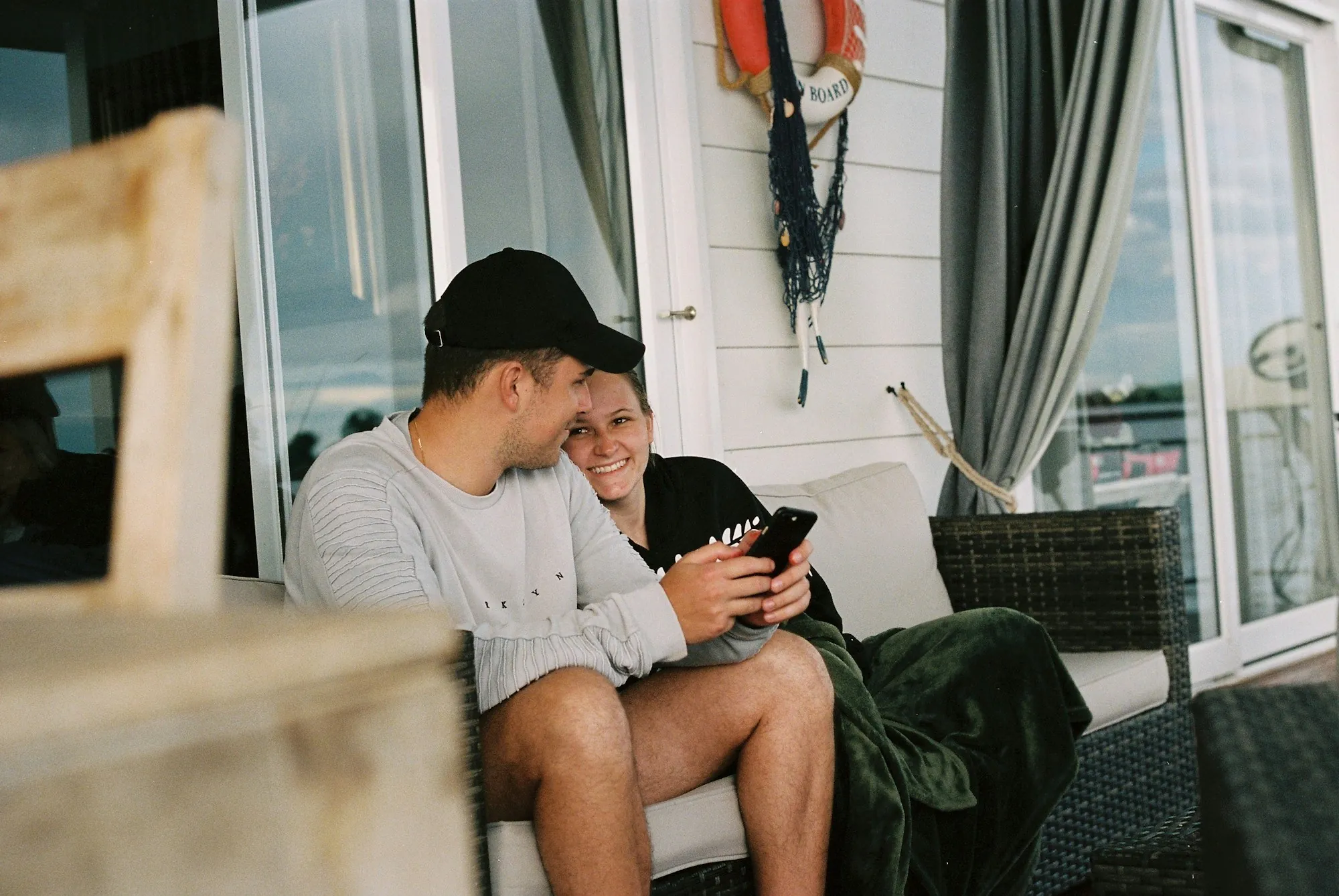 Couple smiling at a phone while relaxing on a couch